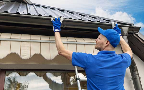 person fixing gutters on a house roof