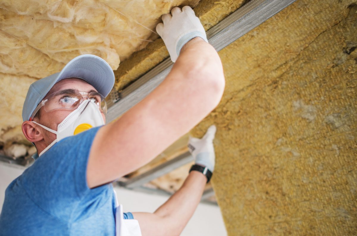 Man with protective mask inspects ceiling insulation.