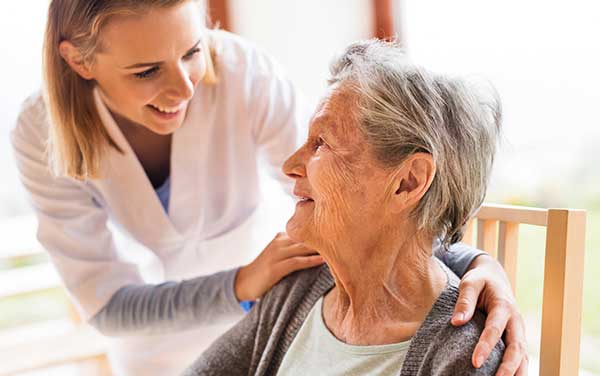 Aged care worker attending to elderly woman.