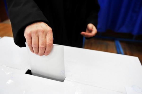 A hand puts a vote in a ballot box