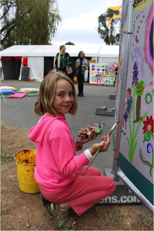 girl painting mural at folk festival