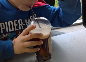 A boy drinking a chocolate milkshake