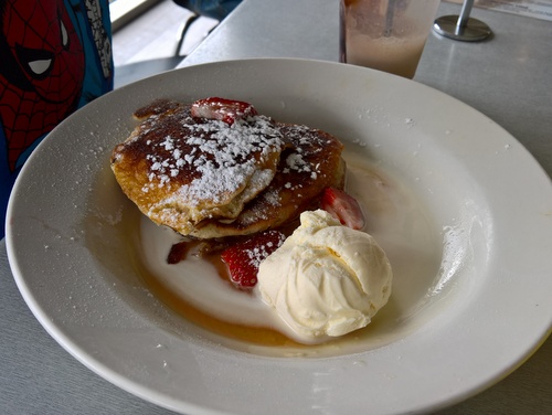 A plate of pancakes with strawberries and ice-cream