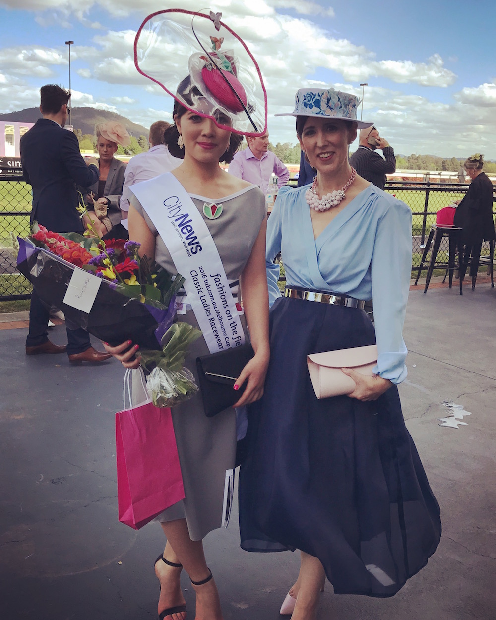 Stephanie Kwong and Sally Martin at the track after Ms Kwong's win in Fashions on the Field. She is wearing a Sovata ensemble while Ms Martin is wearing a skirt she created herself, a vintage blouse and a hat by Bywong milliner Barbara Burton. Photo: Charlotte Harper