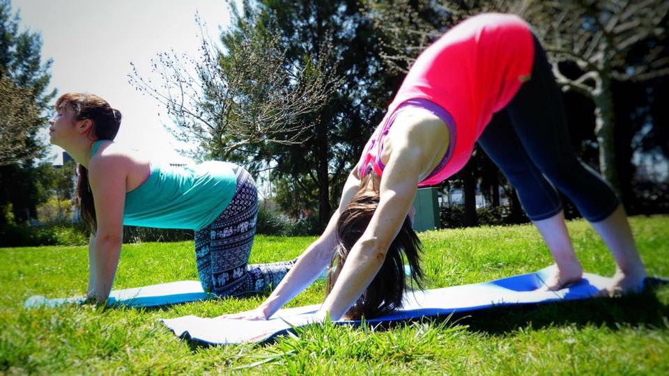 Two women doing yoga in park.