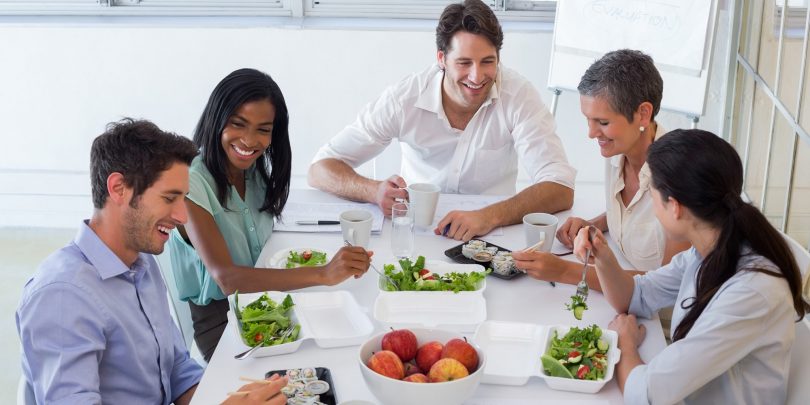 people around a table eating healthy food. 