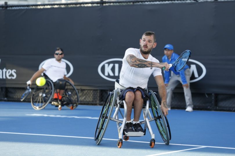 Man playing tennis in a wheelchair.