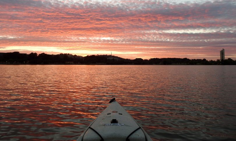 View from the front of a kayak towards the Carillon across Lake Burley Griffin at sunrise