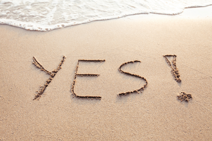 Yes sign written on the sand at a beach.