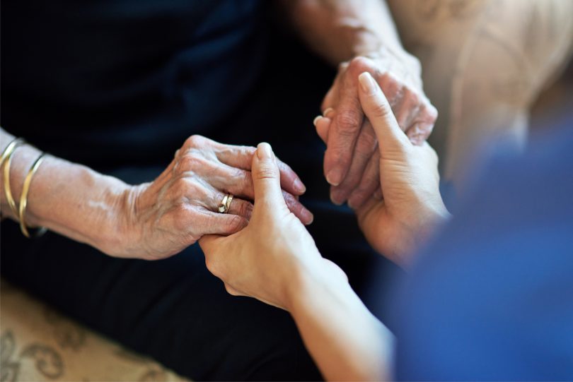 Cropped shot of a nurse holding an elderly woman’s hands compassionately.