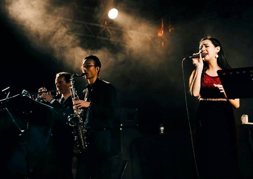 Photograph of Caitlin Magee singing on stage with band