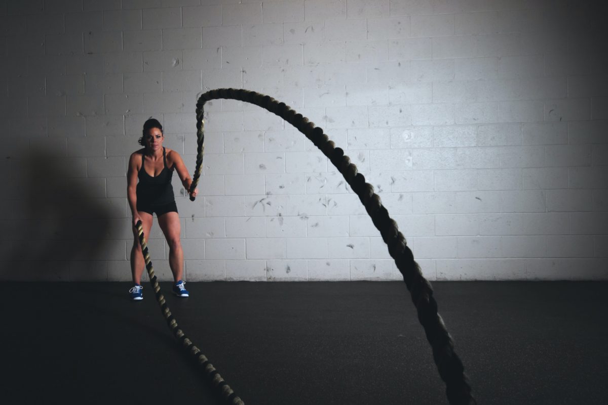 a person swinging ropes in a gym