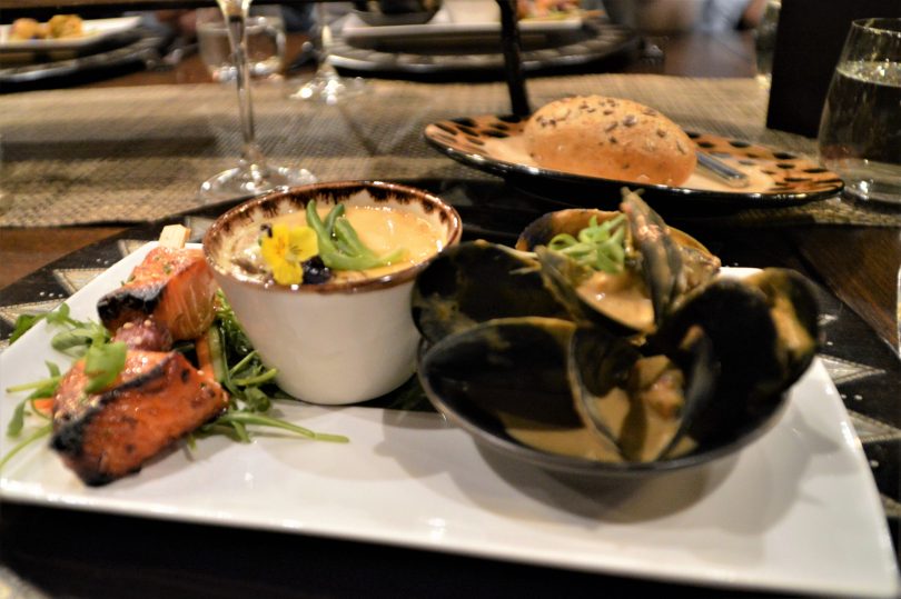 An entree tasting plate of yellow curry coconut mussels, Miso and honey-cured salmon sosatie and egg custard with blue swimmer crab. 