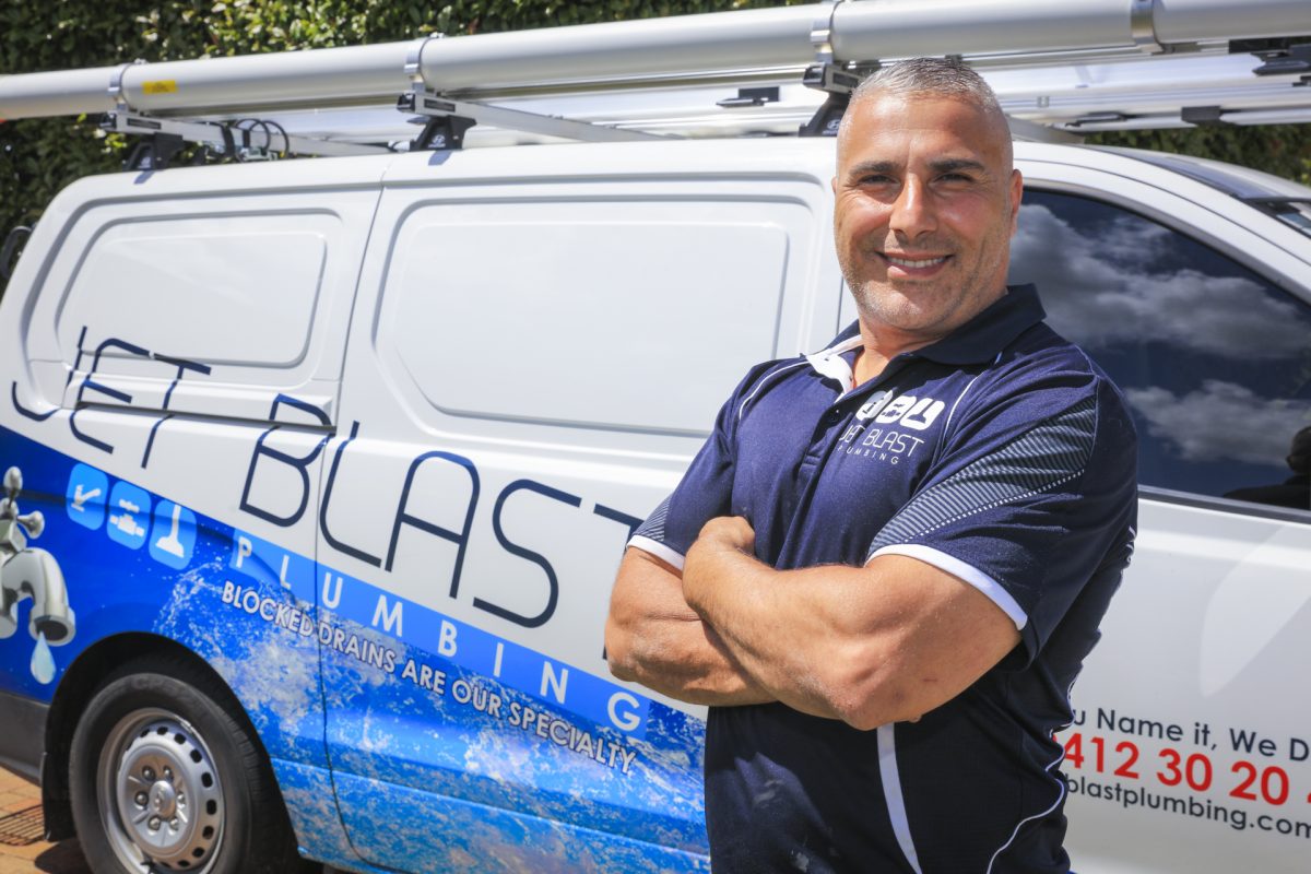 a man with crossed arms standing in front of a branded van