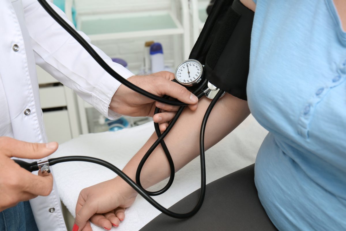 Doctor measuring blood pressure of woman in hospital