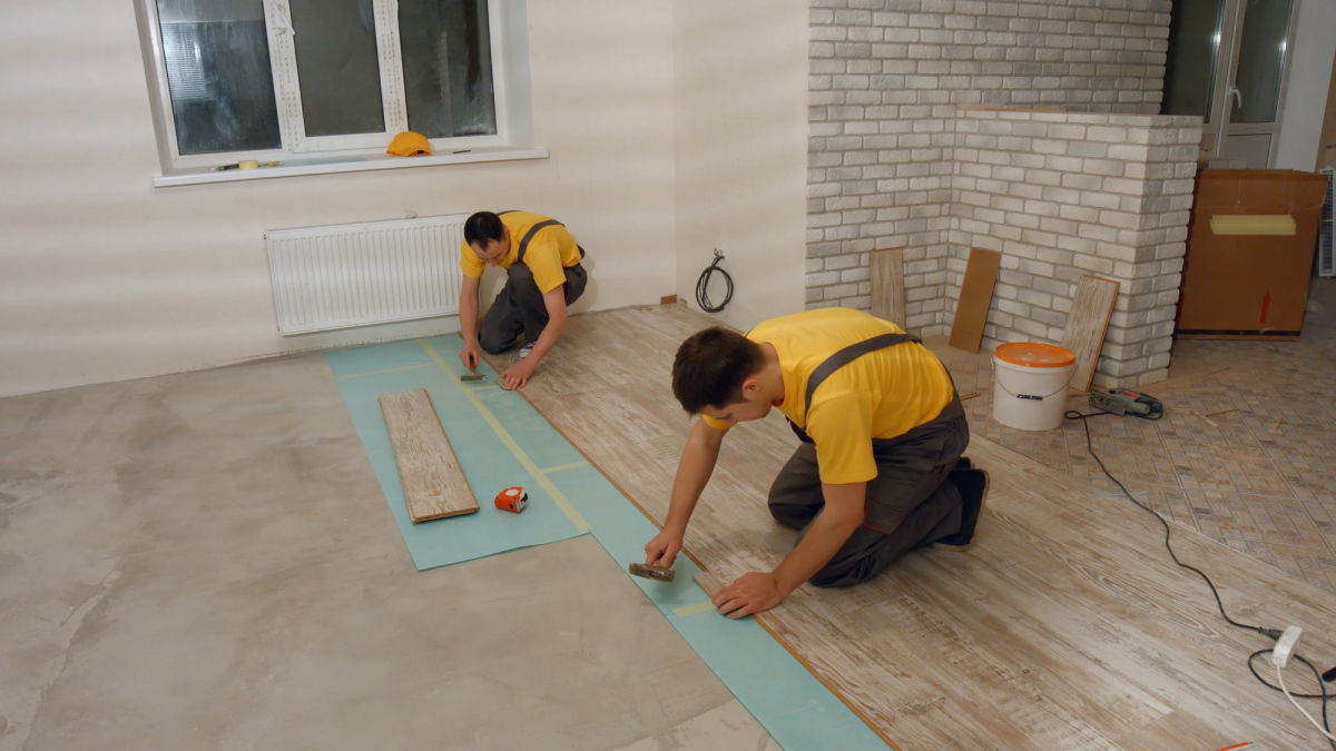 two people laying laminated floor boards in a house