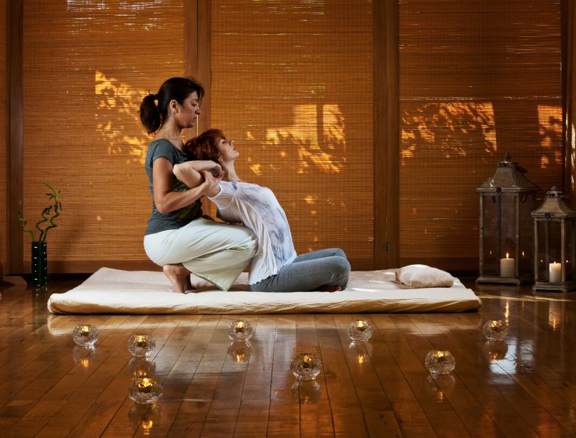 A woman receiving a Thai massage treatment from a masseuse