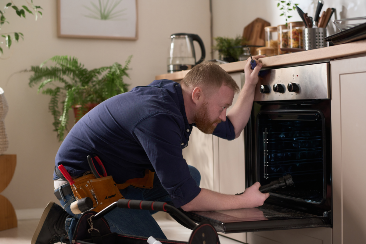 A man repairing an oven in a kitchen