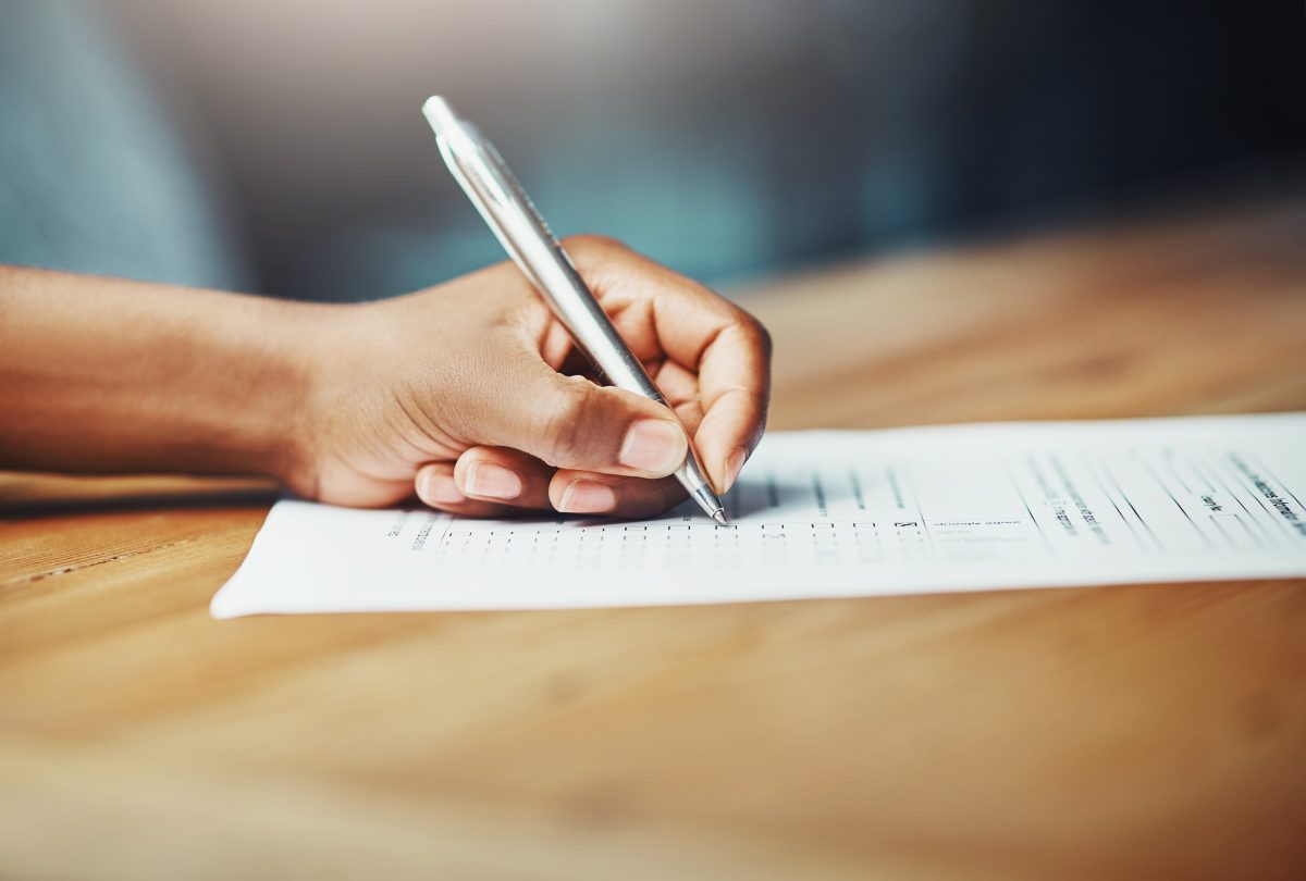 Left hander fills in a form with a pen.