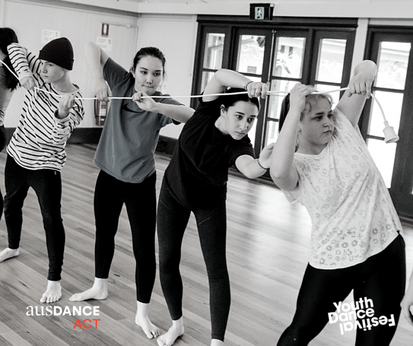 Dancers yoked by electrical cord.