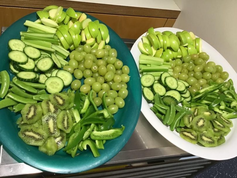 Plates of green fruit and vegetables.