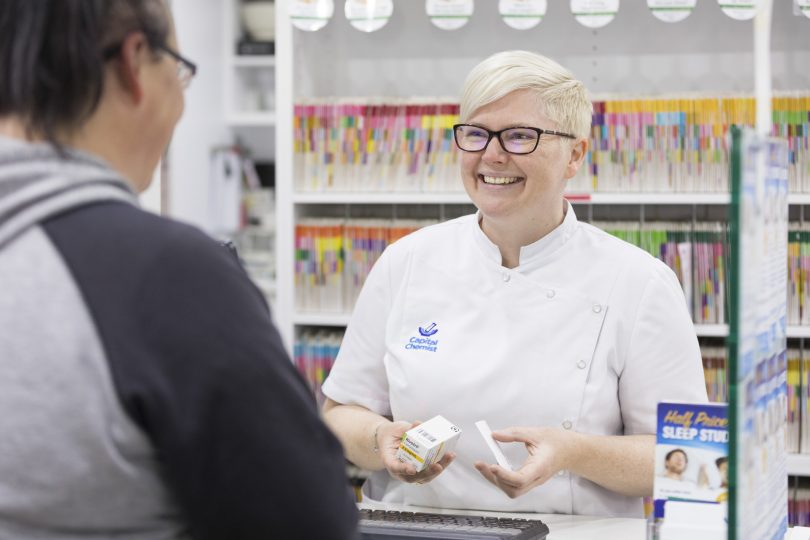 A pharmacist talks to a customer at a chemist.