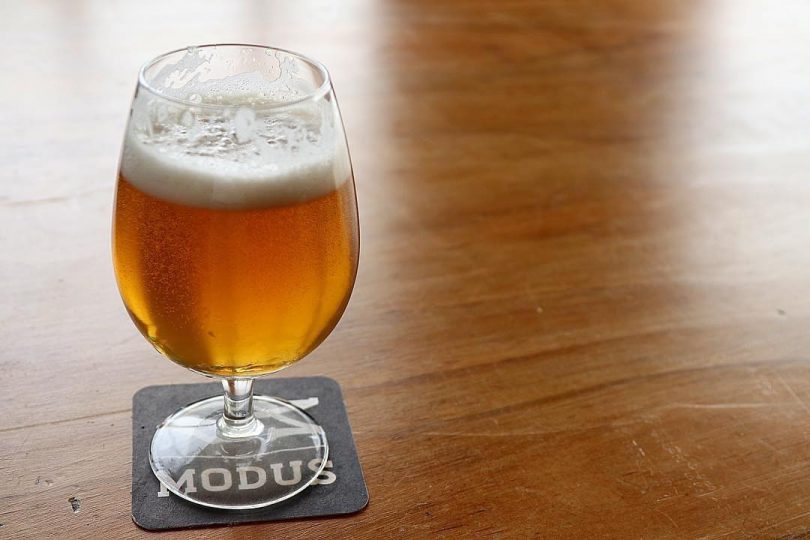 Glass of beer on coaster on table.