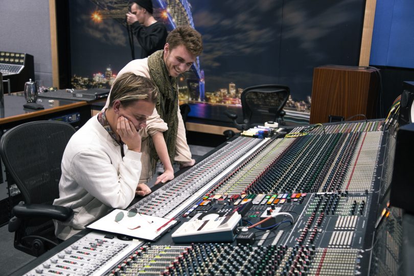 Photograph shows two people at mixing desk