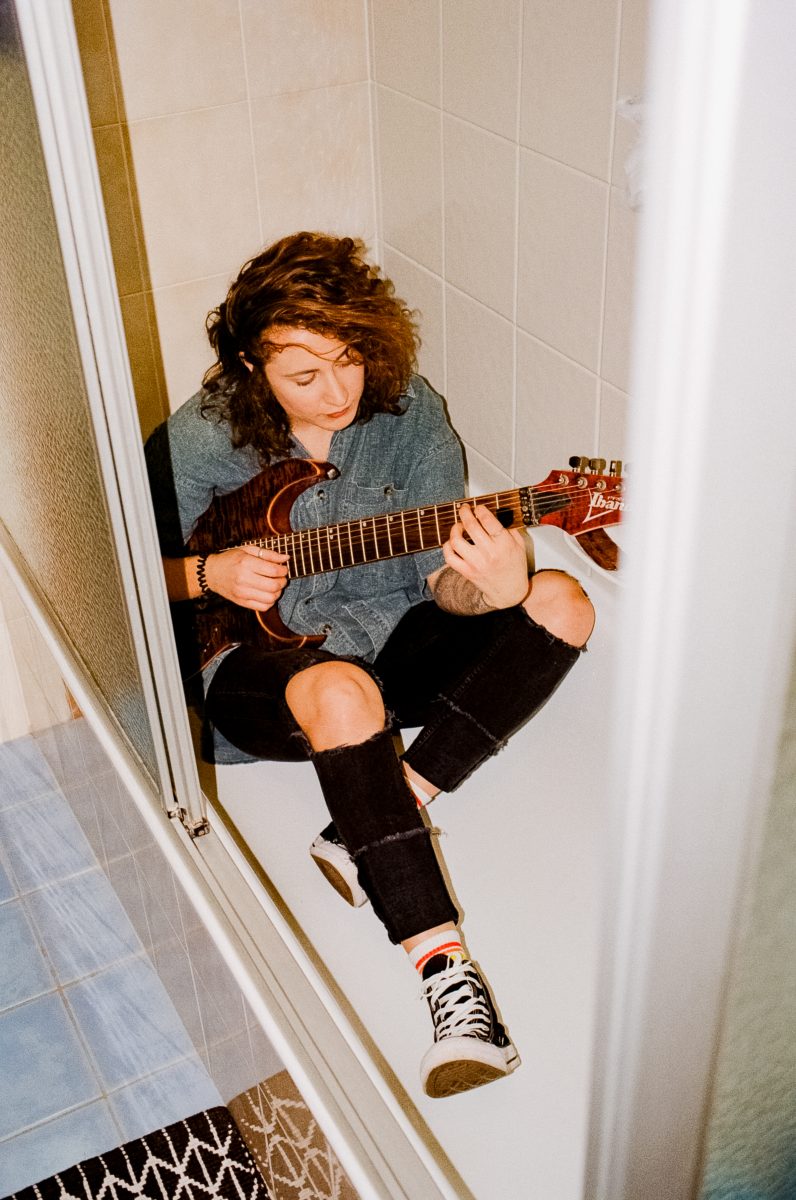 Photograph shows Hope Wilkins sitting in the bath with her guitar