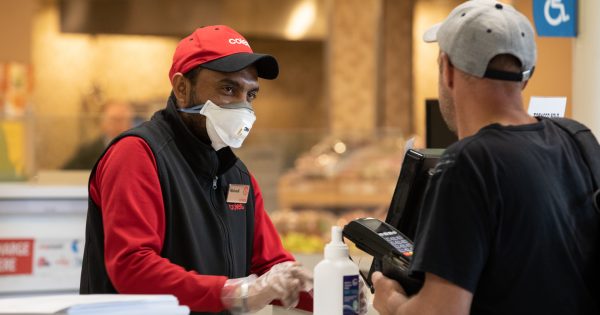 Stoic supermarket workers providing essential services during COVID-19 pandemic