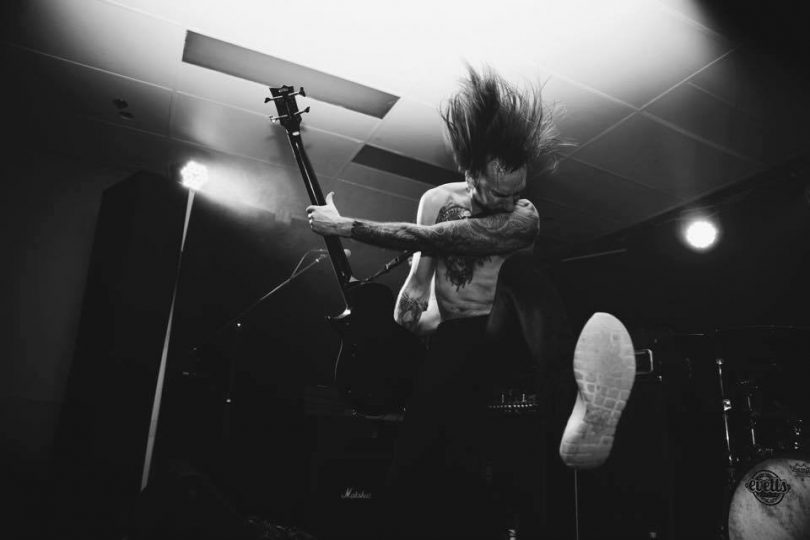 Guitarist airborne while performing onstage. 