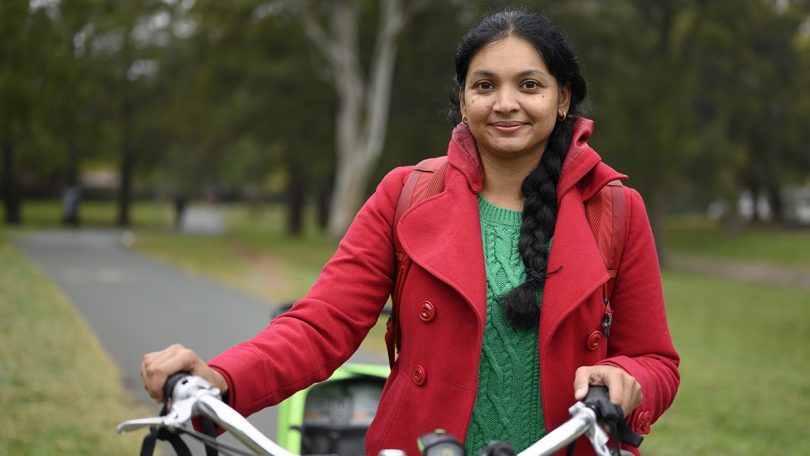 ANU's Dr Aparna Lal standing in park with bike.