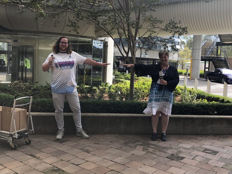 Ben Osborne, left, and Tonya Moss, right, standing apart holding hand sanitiser.