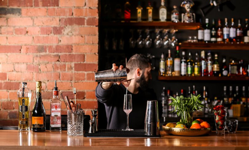 Soumi Tannous behind bar pouring cocktails at Beirut Bunker Bar.