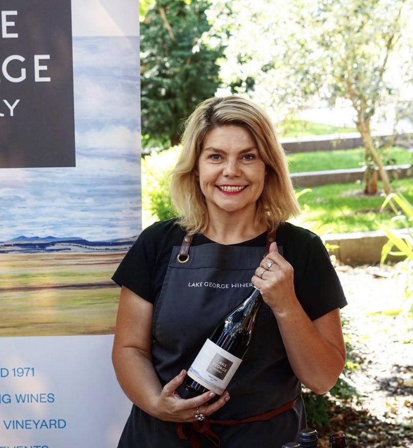 Sarah McDougall holding bottle of red wine.