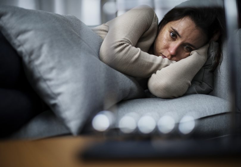 Woman lying on couch looking worried