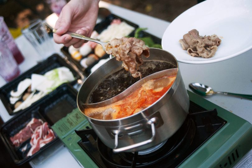 Cooked beef being removed from pot of soup.