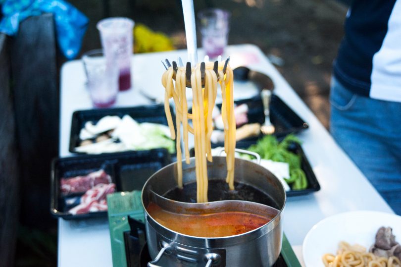 Cooked noodles being taken out of pot of soup.