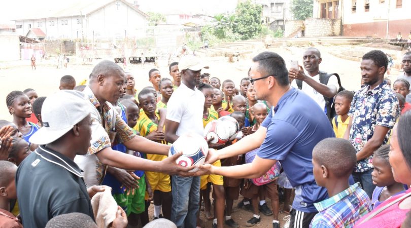 Kitsana "Jimmy" Muongsene handing over a donated football an African community.