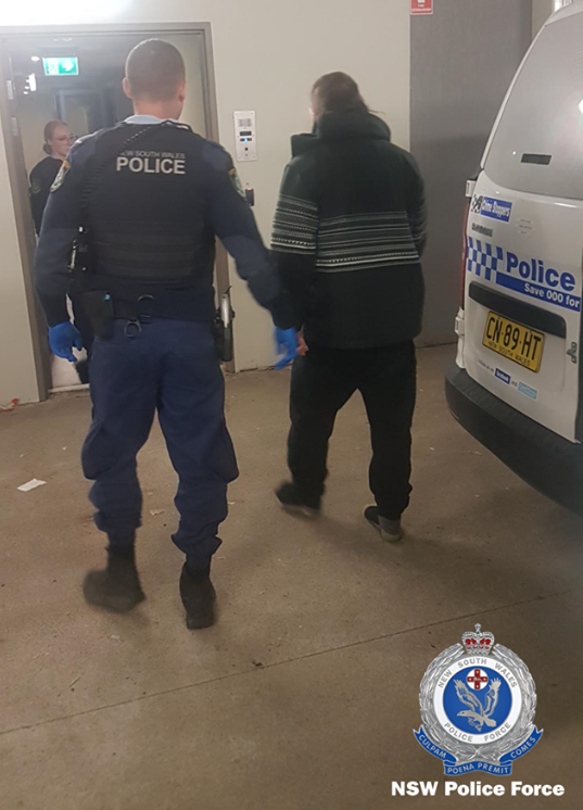 Man being escorted at Queanbeyan Police Station.