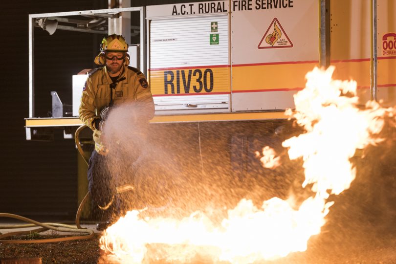 ACT RFS firefighter fighting fire with hose.