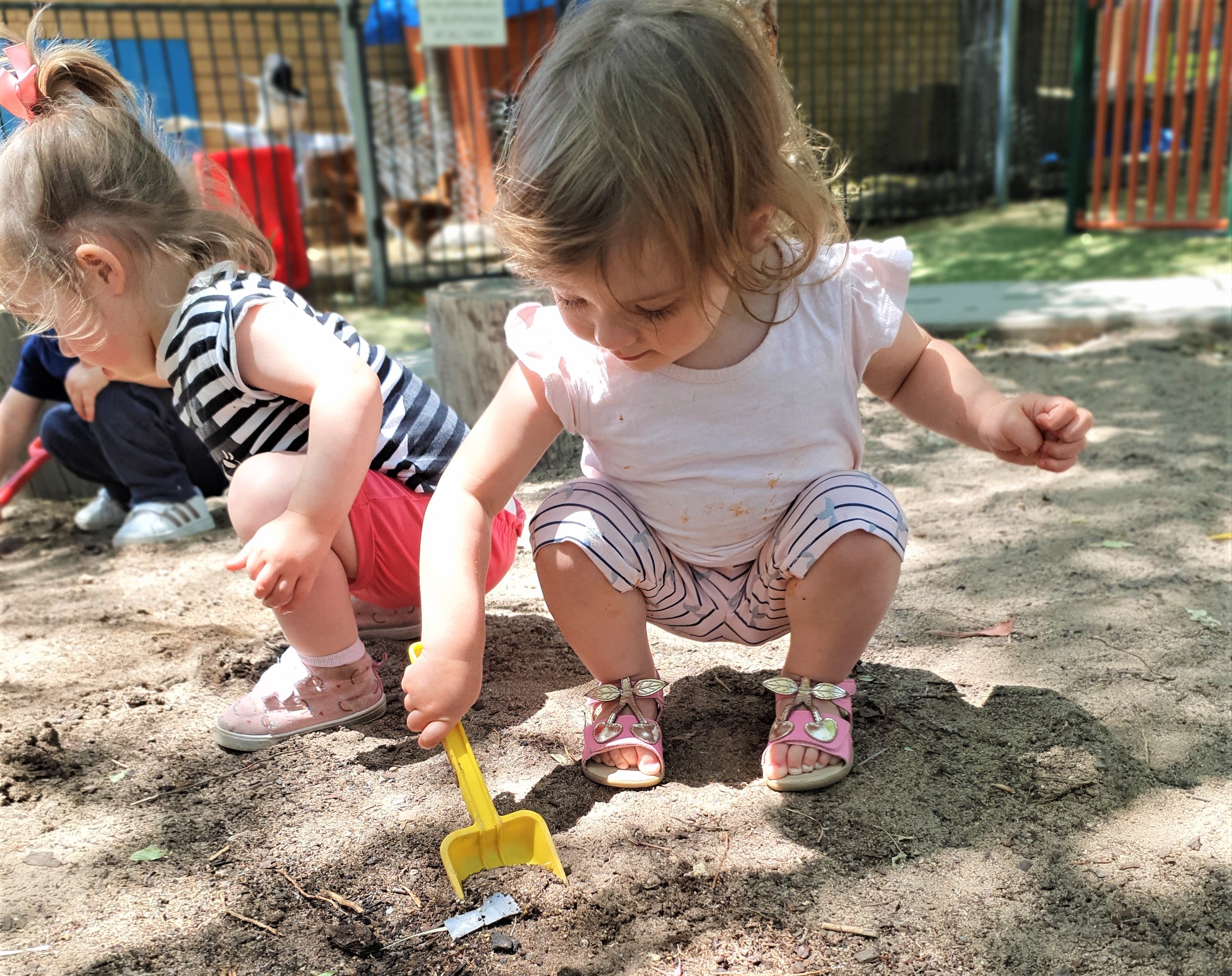 Toddler digging soil with plastic shovel at Richardson Child Care and Education Centre.