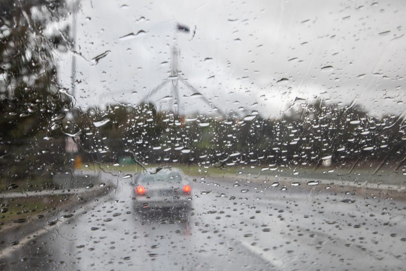 Wet windscreen of car driving towards Parliament House.