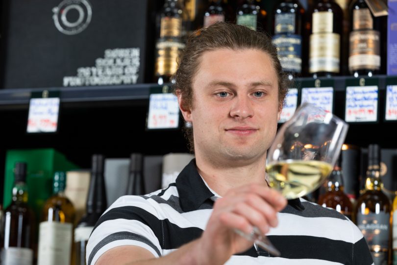 Dave Winmill holding glass of wine at Farrah's Liquor Collective.