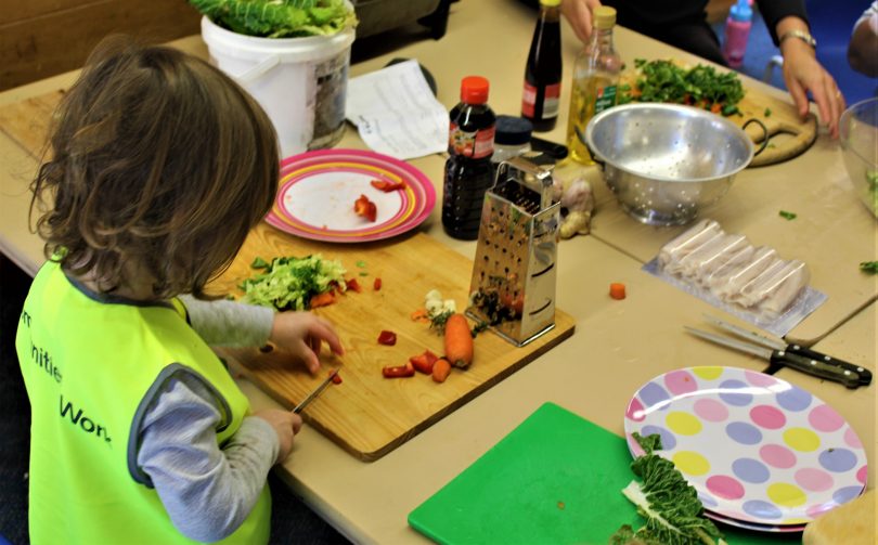 Child slicing vegetables in playgroup.