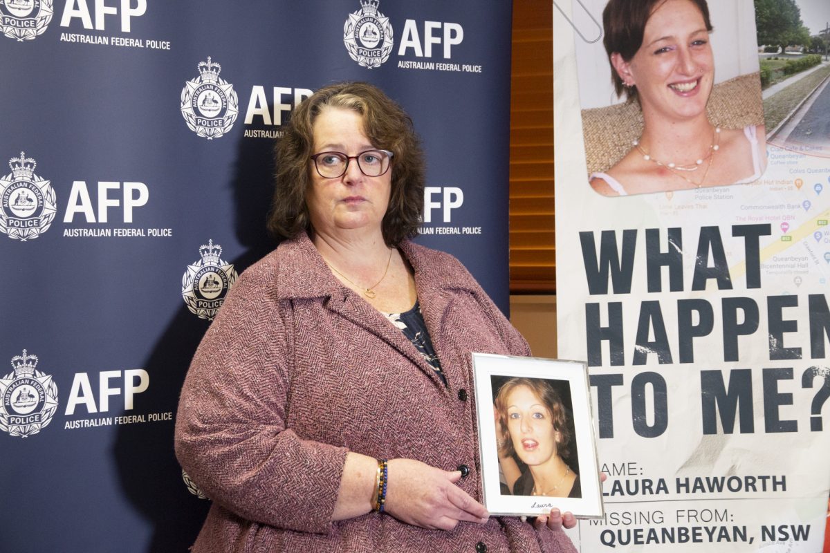 woman holding photo near missing person sign