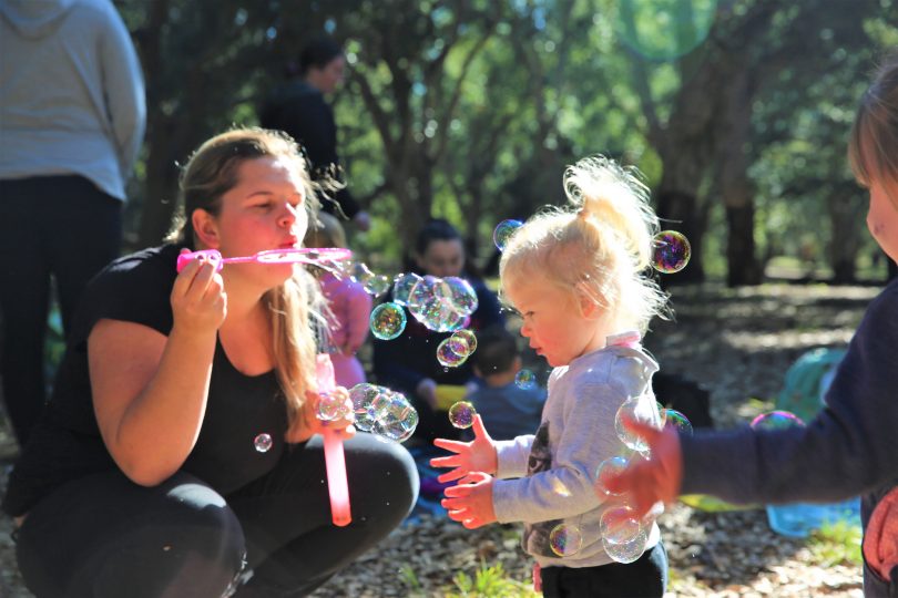 Communities@Work educator blowing bubbles towards child.