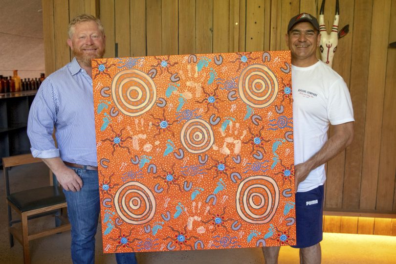 Dean Hall and Richie Allan holding Indigenous artwork.