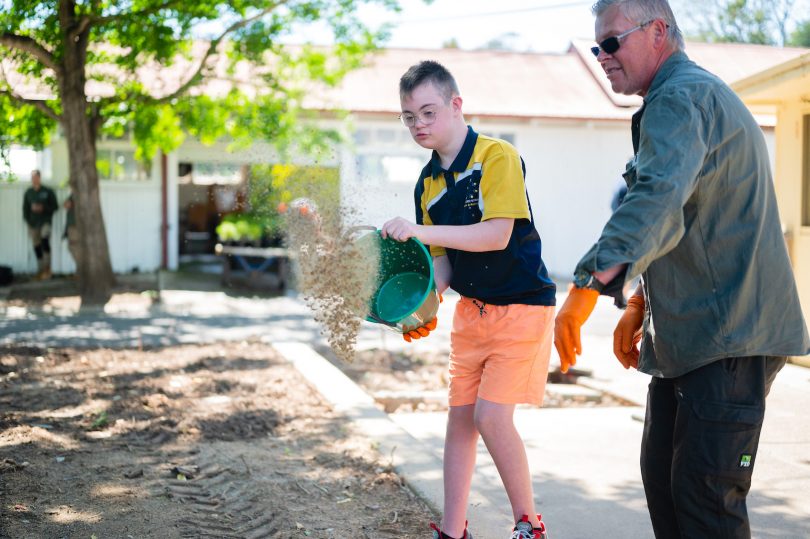 Student from the Woden School spreading seed and growing medium on Ngunnawal garden.