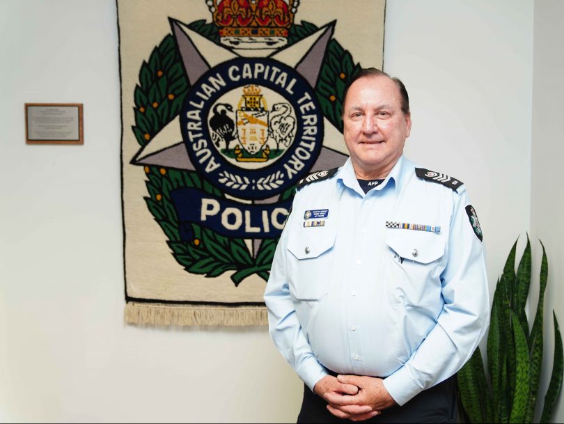 Sergeant Garry Noble with the ACT Police badge tapestry at Canberra City Police Station.